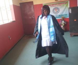 Isata Kamara in a graduation gown celebrating her graduation from cosmetology training.